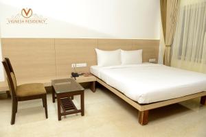 a bedroom with a bed and a desk and a chair at Vignesh Residency in Tiruchchirāppalli