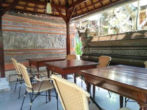 a dining room with wooden tables and chairs at Nuriani Guest House in Ubud