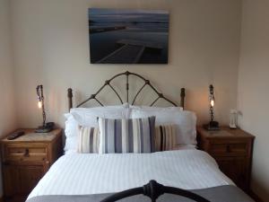 um quarto com uma cama branca com duas mesas de cabeceira em Gunnado em St Austell