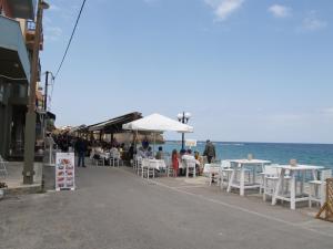 a group of people sitting at tables on the beach at Brigitte house in Chania Town