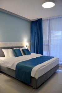 ワルシャワにあるJessApart – Ochota Apartmentsの青いカーテン付きのベッドルームの大型ベッド1台