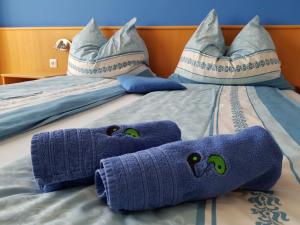 Una cama con toallas azules y almohadas. en Gästehaus Lokalaugenschein, en Podersdorf am See