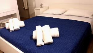 a bed with rolled towels on a blue sheet at Casetta Maremè in San Vito lo Capo