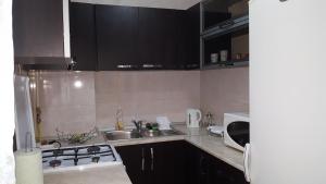 eine Küche mit schwarzen Schränken, einer Spüle und einer Mikrowelle in der Unterkunft Apartament Matei in Constanţa