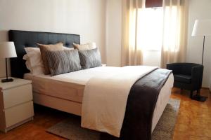 a bedroom with a bed and a chair and a window at Casa do Parque in Lagos