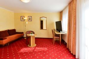 a hotel room with a couch and a tv and a table at Gasthof Mühlwinkl in Staudach-Egerndach