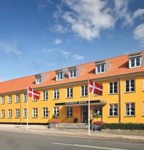 un bâtiment jaune avec des drapeaux canadiens devant lui dans l'établissement Gentofte Hotel, à Gentofte