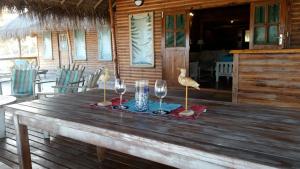 a wooden table with wine glasses and a bird on it at Pura Vida Lodge in Morrumbene