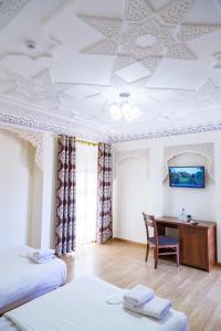 a bedroom with two beds and a desk with a mirror at Hotel Volida Boutique in Bukhara