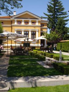 a building with tables and umbrellas in a park at Kokoshkovata Boutique House in Samokov