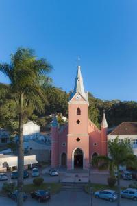 a pink church with a clock tower in a parking lot at Dom Pedro Hotel in Petrópolis