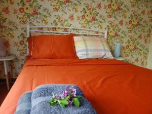 a bed with an orange comforter and flowers on it at Floral Tribute Studio in Kavála