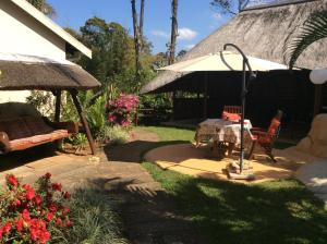 un patio con una mesa, una sombrilla y algunas flores en Tropical Paradise, en Southbroom