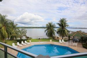 a swimming pool with chairs and a view of the water at Xingu Praia Hotel in Altamira