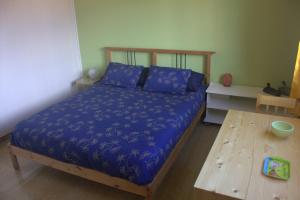 コマッキオにあるFiore delle Valliのベッドルーム1室(青いシーツと木製テーブル付きのベッド1台付)