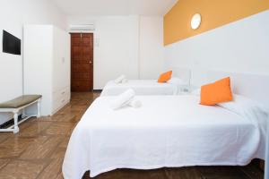 two beds in a white room with orange pillows at Hostal Alicante in San Antonio