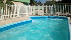 リンドーイアにあるPousada Encanto Das Aguasの白い柵の前の青いスイミングプール