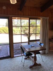 un tavolo e delle sedie in una stanza con finestre di Rose Cottage a Metung