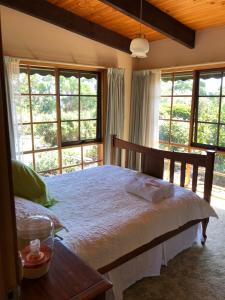 una camera da letto con un grande letto e ampie finestre di Rose Cottage a Metung