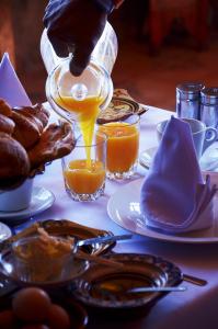 a person pouring orange juice into a glass on a table at Riad Chay & Boutique in Ouarzazate