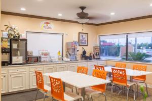 un restaurante con una mesa blanca y sillas naranjas en Super 8 by Wyndham Houston/Willowbrook Hwy 249, en Houston