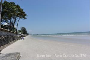 an empty beach with palm trees and the ocean at Bann Imm Aem Condo No.376 in Hua Hin
