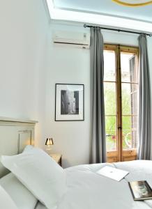 a bedroom with two white beds and a window at Hostal Girona in Barcelona
