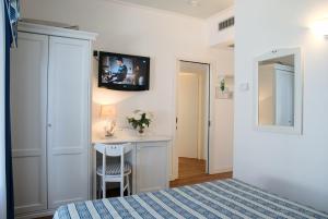 a bedroom with a bed and a desk with a tv on the wall at Hotel La Goletta in Lignano Sabbiadoro