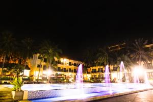 a fountain in front of a building with palm trees at Hon Rom Central Beach Resort in Mui Ne