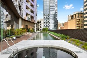 a pool in the middle of a city with tall buildings at Luxuria Apartments - EQ Tower in Melbourne