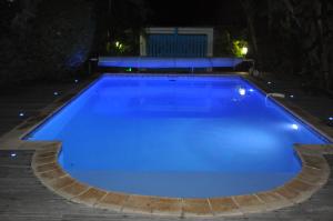a large blue swimming pool at night at Ti Joli Caz en Bois in Saint-Gilles-les Hauts
