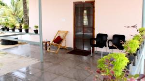 Homested Homestay Fort Kochi في كوتشي: غرفة بها كراسي وطاولة وبعض النباتات
