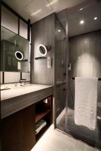 a bathroom with a shower and a sink and a mirror at The Emperor Hotel in Hong Kong