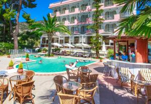 un patio del hotel con mesas y sillas y una piscina en Tolon Holidays Hotel, en Tolo