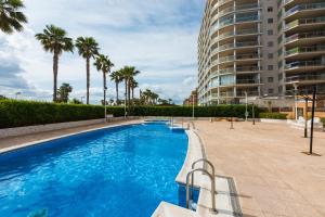 una piscina con palmeras y un gran edificio en Vistamar Departamento, en Oropesa del Mar