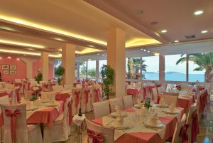 a banquet hall with tables and chairs with red tablecloths at Tolon Holidays Hotel in Tolo