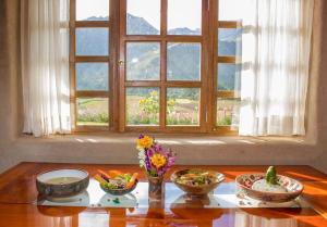 a table with bowls and flowers on a table with a window at Inkasaire Boutique Lodge in Urubamba