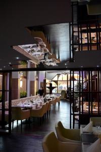 a restaurant with tables and chairs and a person in the background at Hotel Minerva in Mosonmagyaróvár