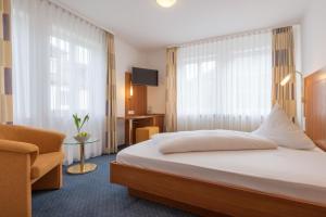 Braunsbach的住宿－施洛斯多廷根酒店，配有一张床和一把椅子的酒店客房