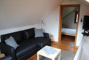 uma sala de estar com um sofá preto e uma mesa em 't Huizeke em Asse