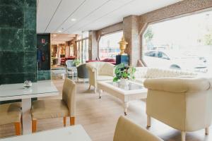 einen Salon mit Stühlen, Tischen und einem Fenster in der Unterkunft Hotel Embajador in Almería