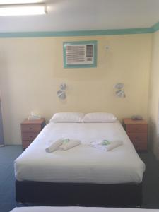 a bedroom with a white bed with two towels on it at John Oxley Motel in Port Macquarie