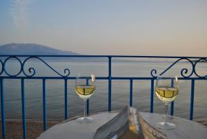 zwei Gläser Weißwein auf einem Tisch mit Blick auf das Wasser in der Unterkunft Villa "Pietra e Mare" in Nafpaktos
