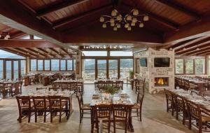 a dining room with tables and chairs and a fireplace at Archontiko Manias in Axós