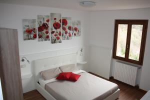 a bedroom with a white bed with a red pillow at Ca Vecia in Gargnano