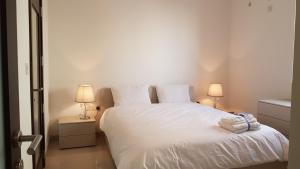 a bedroom with a white bed with two lamps at Sunrise Suites, Apt. 2 in Birkirkara