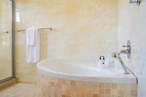 La salle de bains est pourvue d'une baignoire blanche et d'une douche. dans l'établissement Leaves Lodge and Spa, à Nelspruit