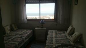 two beds in a room with a window at Figueira House AL in Figueira da Foz