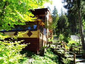 eine Blockhütte im Wald mit einem Zaun und Bäumen in der Unterkunft Complex Vila Balea in Cumpăna