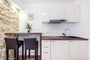 a kitchen with white cabinets and a sink and two chairs at Apartments Palace Rialto in Šibenik
